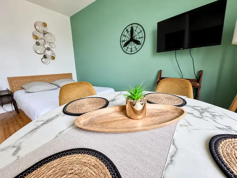 Coin repas, télévision et mur vert d’eau — Appartement meublé à Lorient